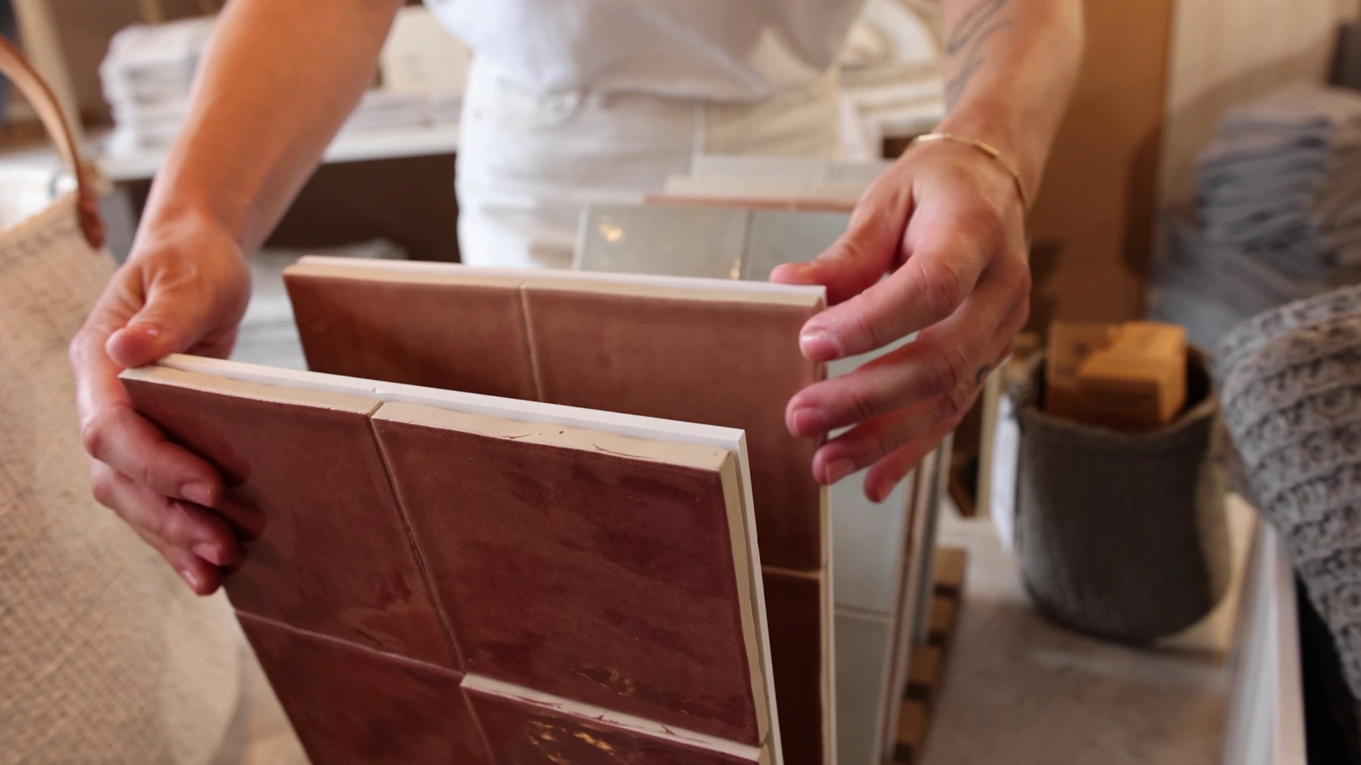 Hände präsentieren großformatige terrakottafarbene Fliesenmuster im Showroom