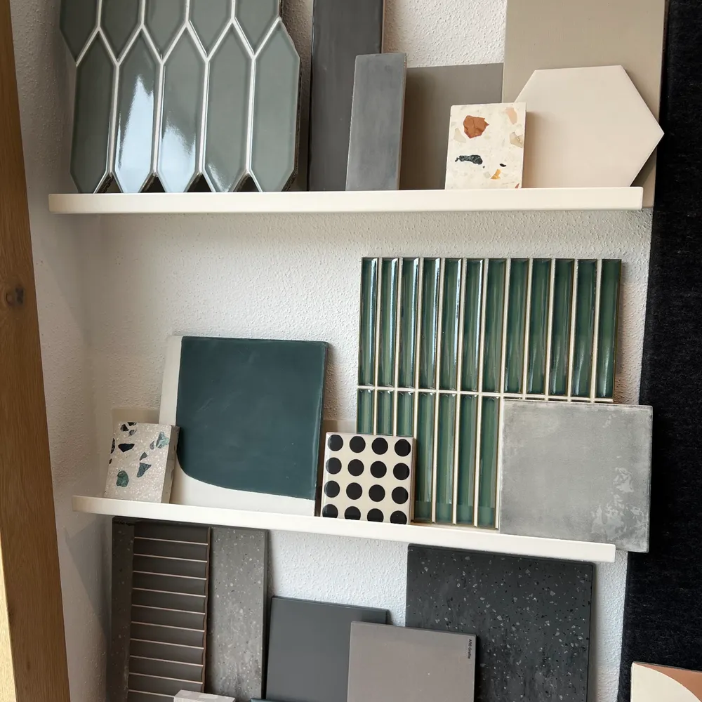 Regal im Showroom mit graugrünen Sechskantfliesen, grauen Fliesen und einer Terrazzo-Kachel